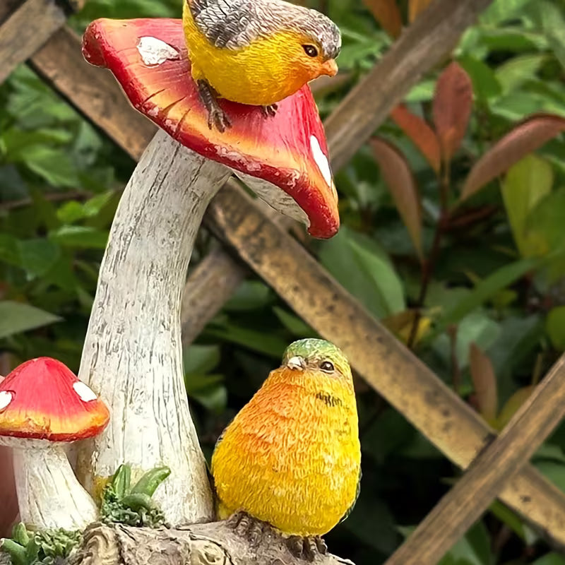 Detail van het paddenstoel tuinbeeld: vogeltje met oranje borst en opgeheven staart zittend op de rand van de vliegenzwamhoed