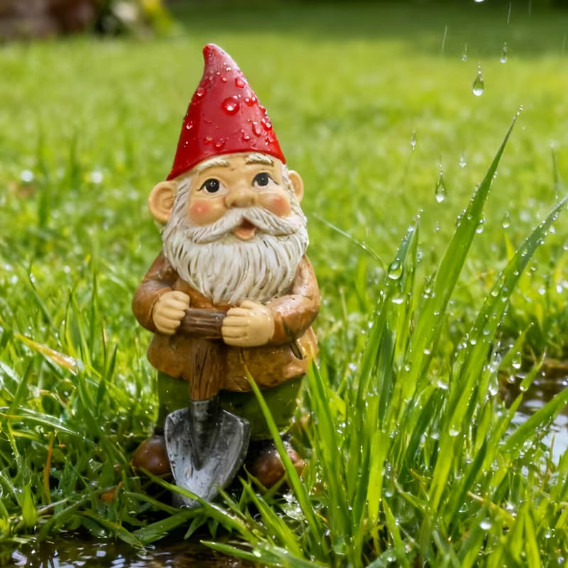 Tuinkabouter met schep van 13,6 cm in nat gras met dauwdruppels op zijn rode puntmuts